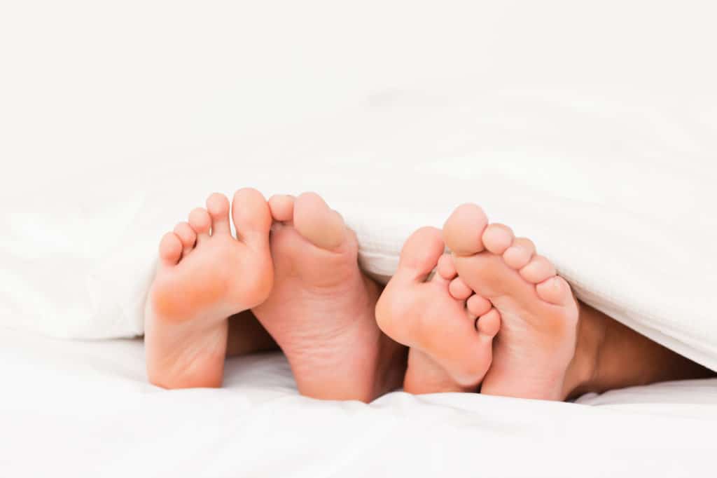 Close up of four feet in a bed - healthy sex 