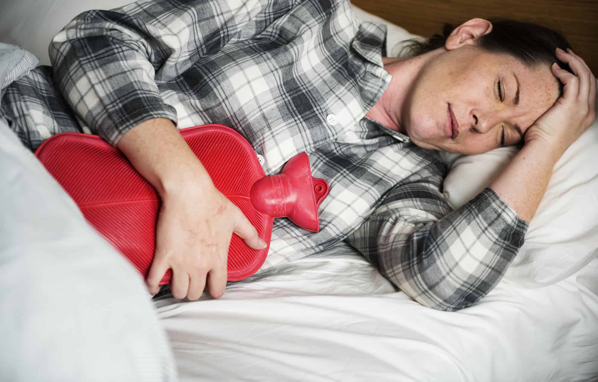 woman using a hot water bottle experiencing period cramps