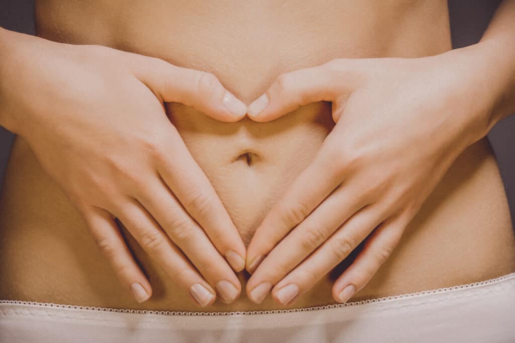 Fit women belly with hands making heart. PMS symptoms or diet concept. uterine prolapse
