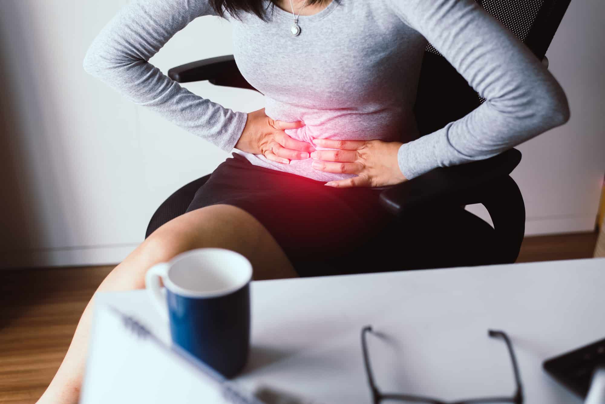 Woman having painful stomach ache during working from home,Female suffering from abdominal pain,Period cramps,Hands squeezing belly,Stomach pain