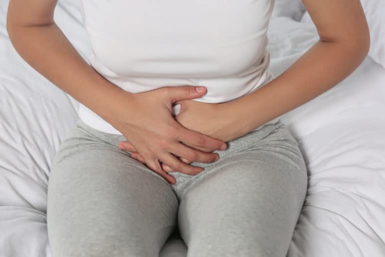 Young woman suffering from pelvic floor tension on bed, closeup