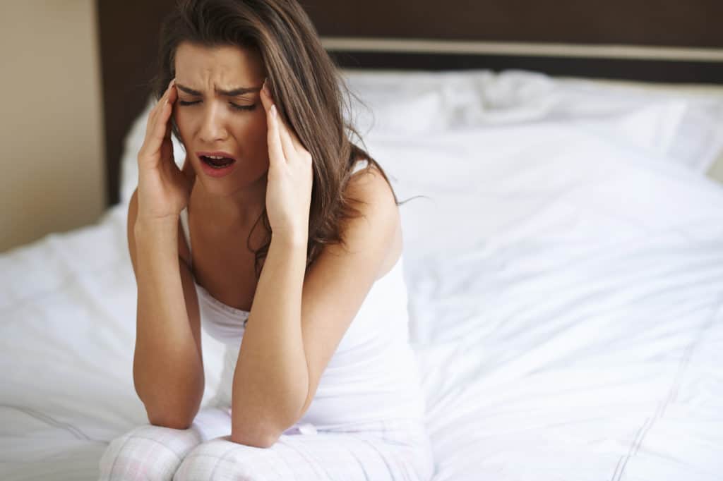 woman in bed with head pain
